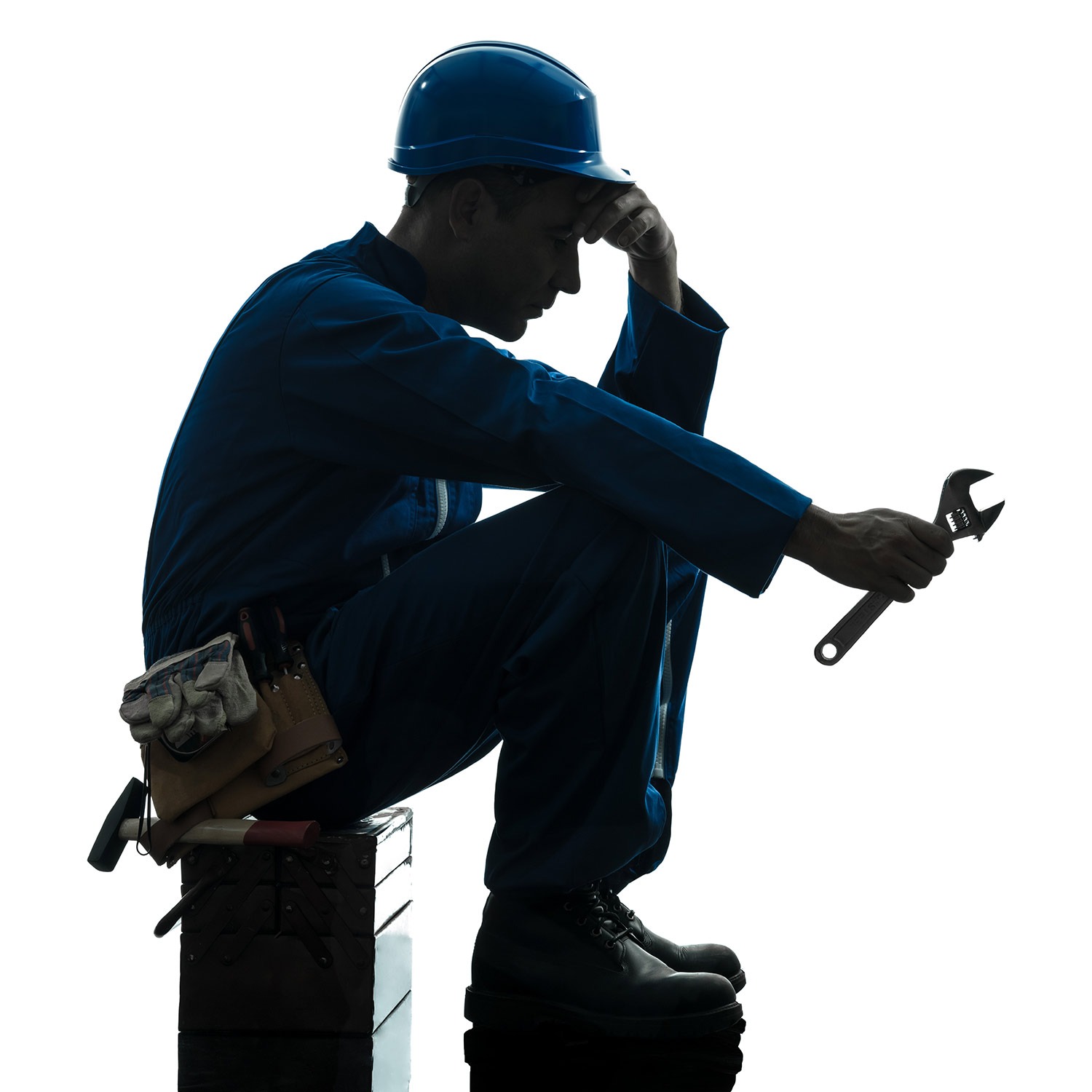 Handwerker sitzt mit aufgestütztem Kopf auf einer Werkzeugkiste.